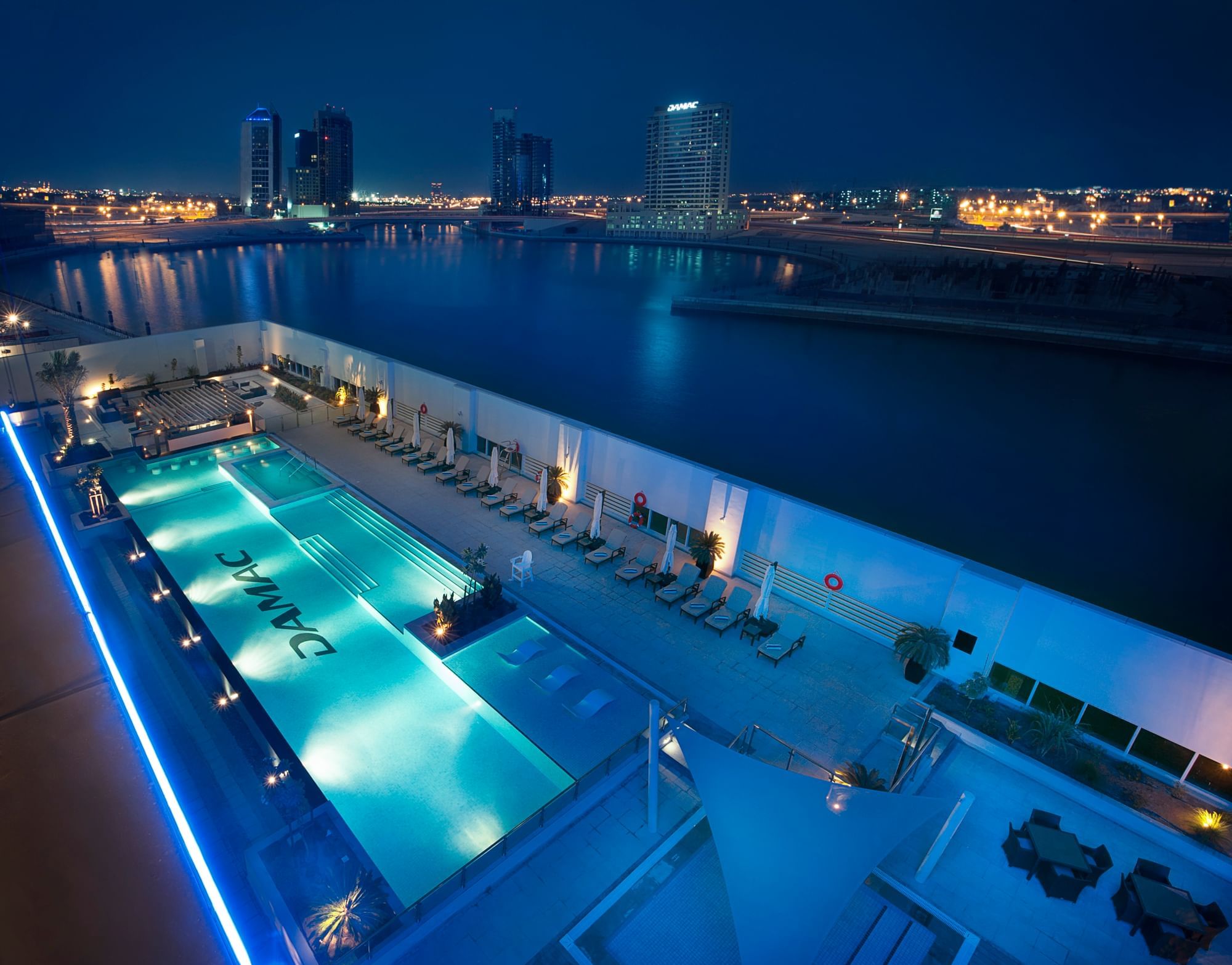 Aerial view of an outdoor pool with attractive night city lights at DAMAC Maison Canal Views