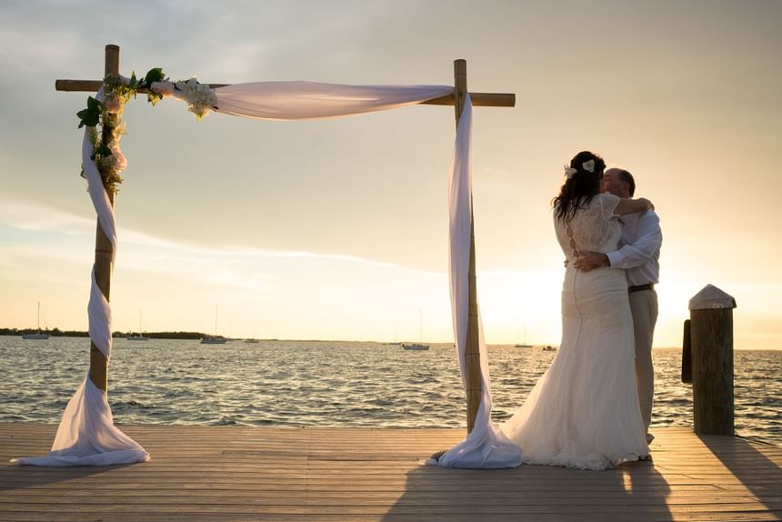 Bride and groom dancing on pier with ocean surrounded by the sunset at Bayside Inn Key Largo