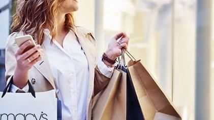 Woman holding shopping bags by a smartphone near Warwick San Francisco