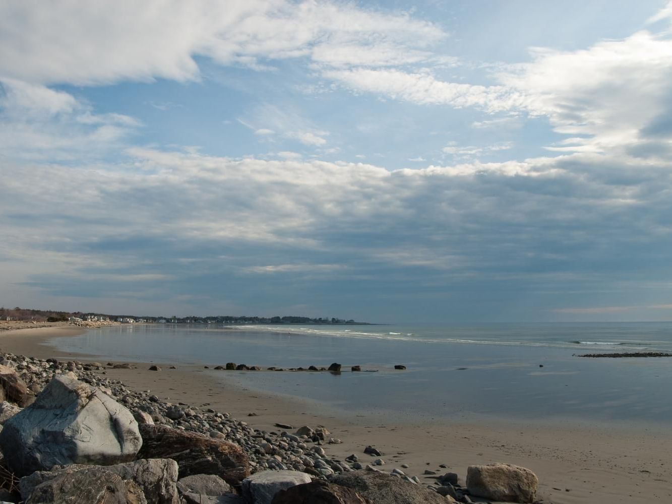 Beach with rocky shoreline and calm water under a cloudy sky at Moody Beach near Anchorage by the Sea