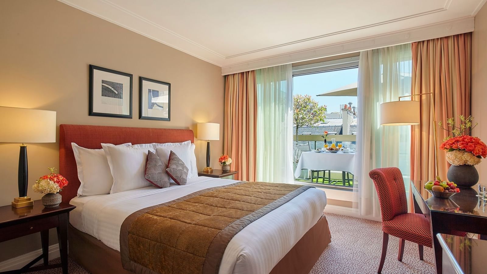 Bed between side tables near a work desk and balcony window with seating in Deluxe Room at Hotel Westminster Paris