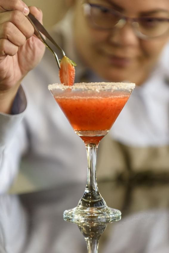 Chef holds a strawberry over a drink at Diez Hotel Categoría
