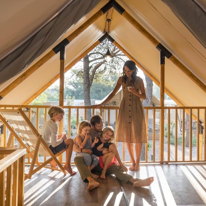 Familie in einem Holzhaus mit Terrasse und Blick auf die Natur.