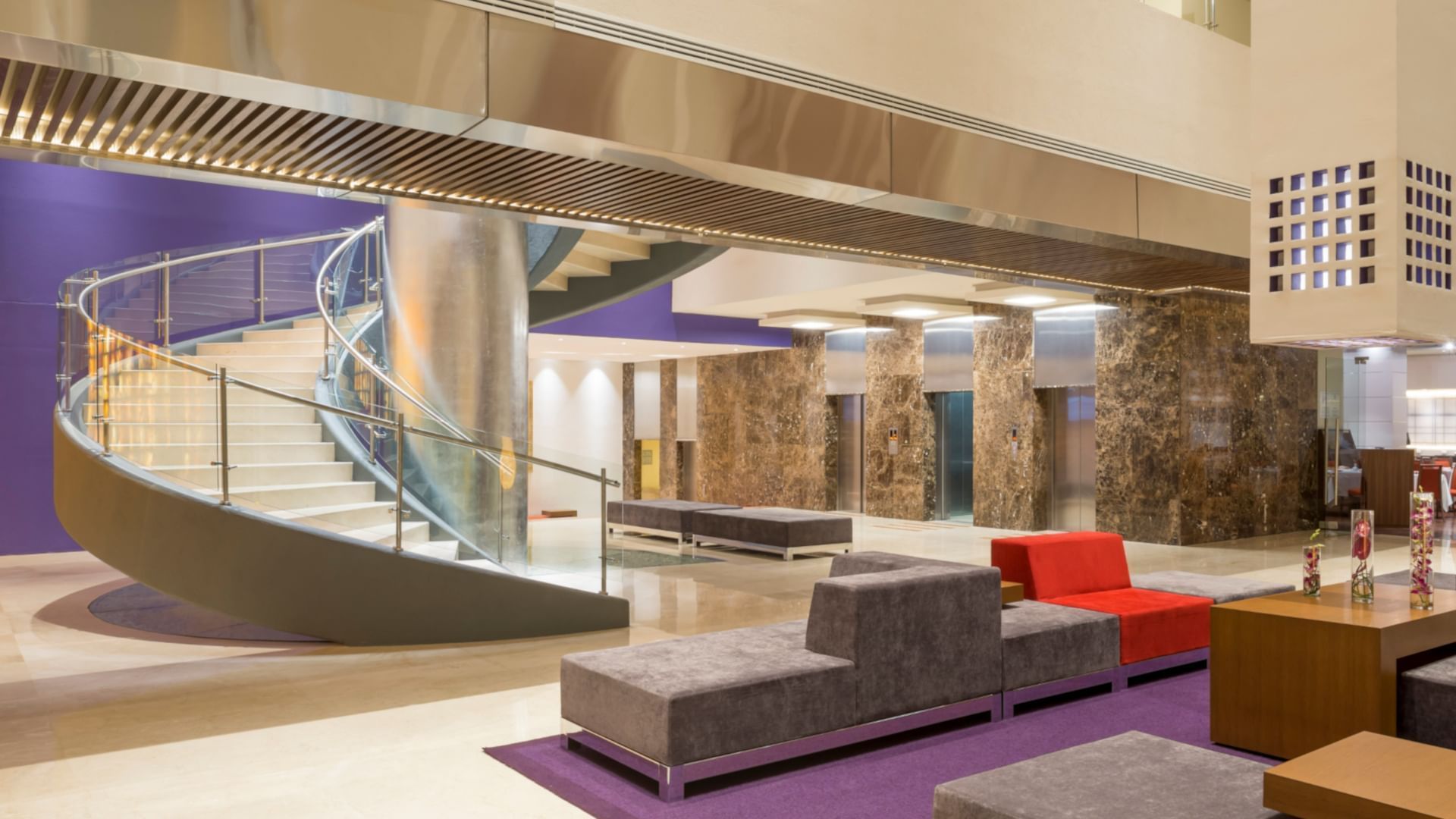 Chic lobby featuring a spiral staircase, purple accents, and plush seating at Camino Real Pedregal Mexico