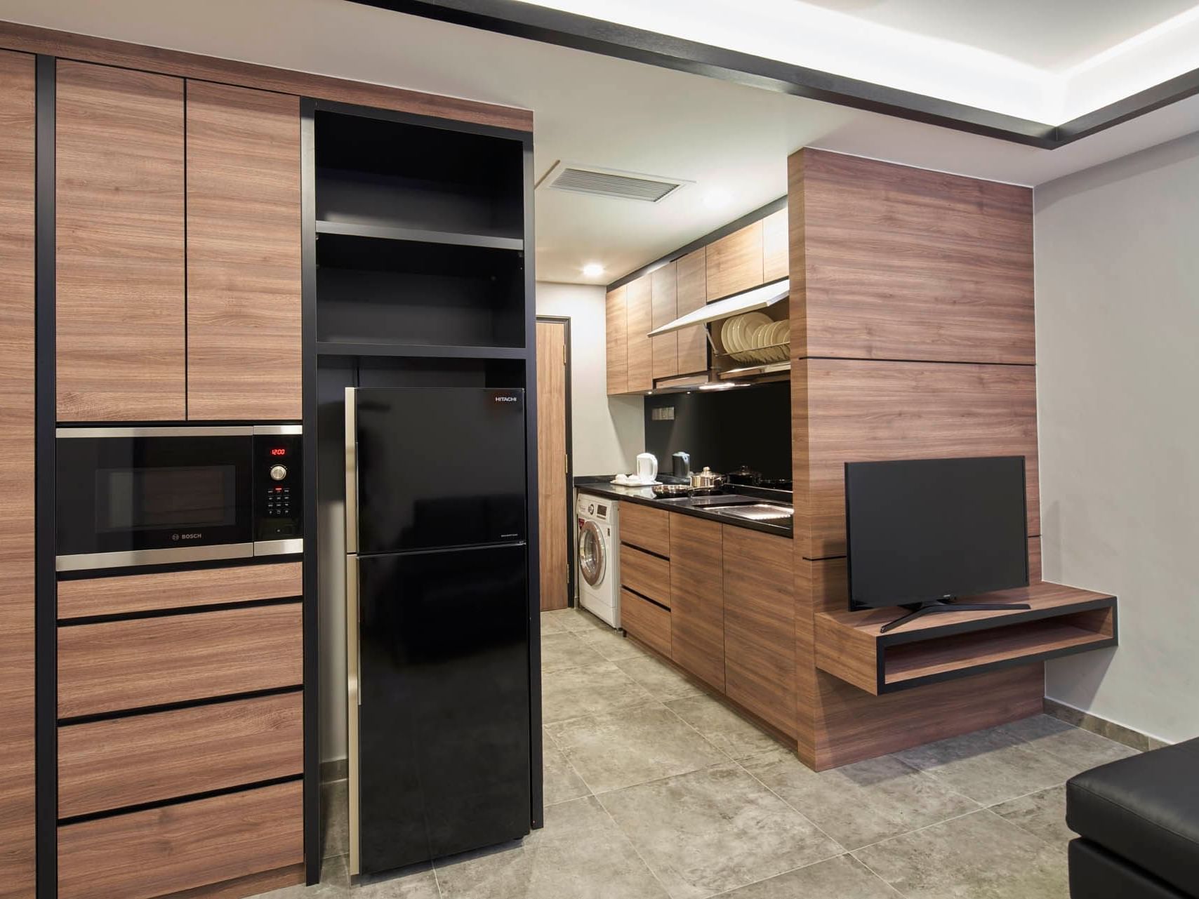 Image 72: Modern Two Bedroom kitchen with wooden cabinets, black appliances, and a TV on grey flooring at Orchard Grand Court