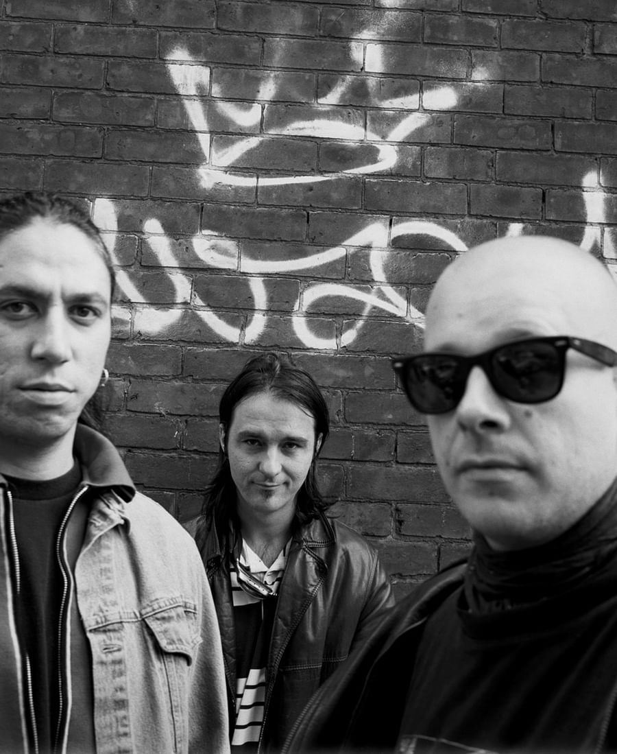 Three people pose in front of a brick wall with graffiti in this black and white photograph at Warwick Le Crystal Montreal