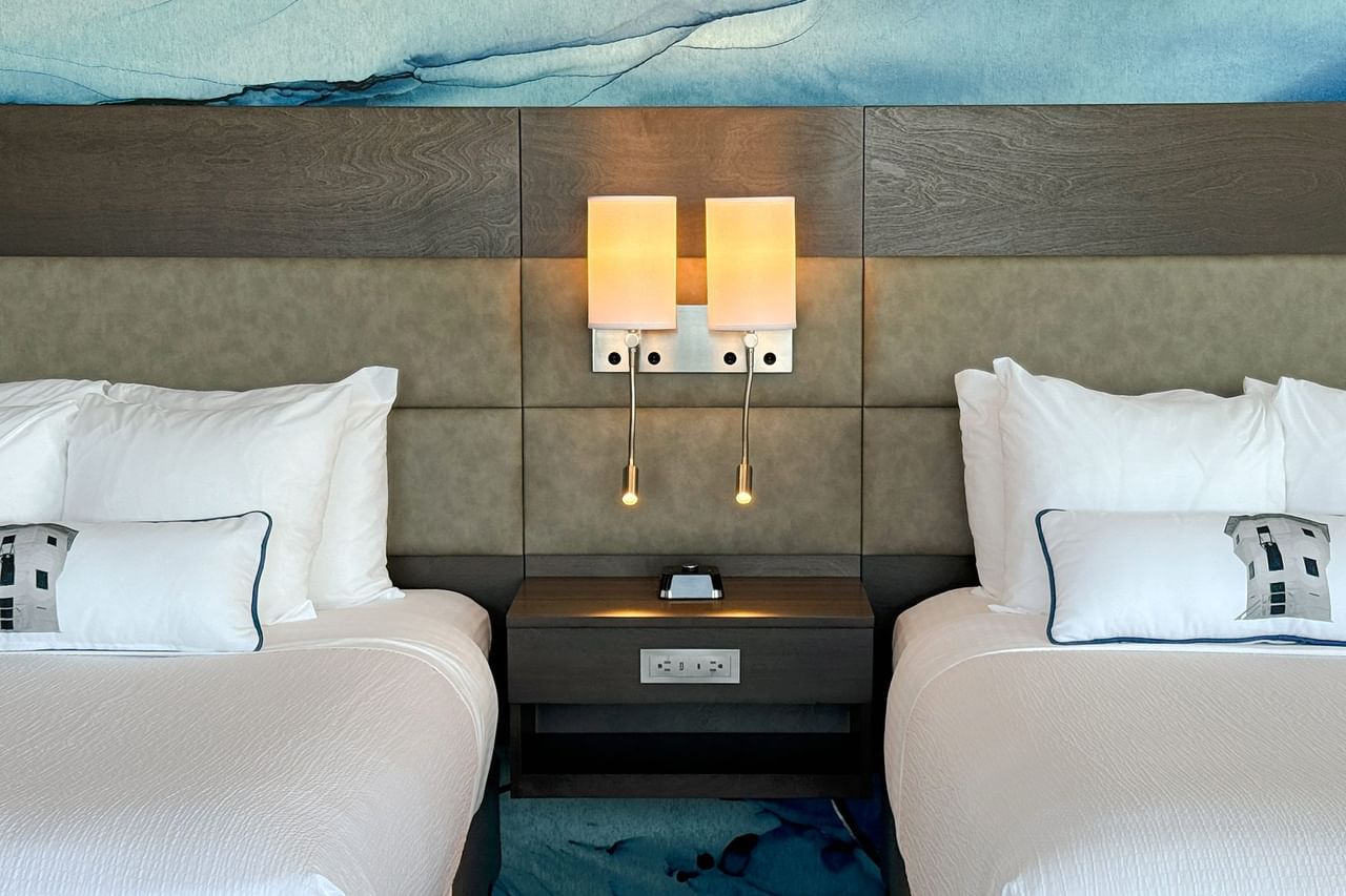 Hotel guestroom with two queen beds, a nightstand and light