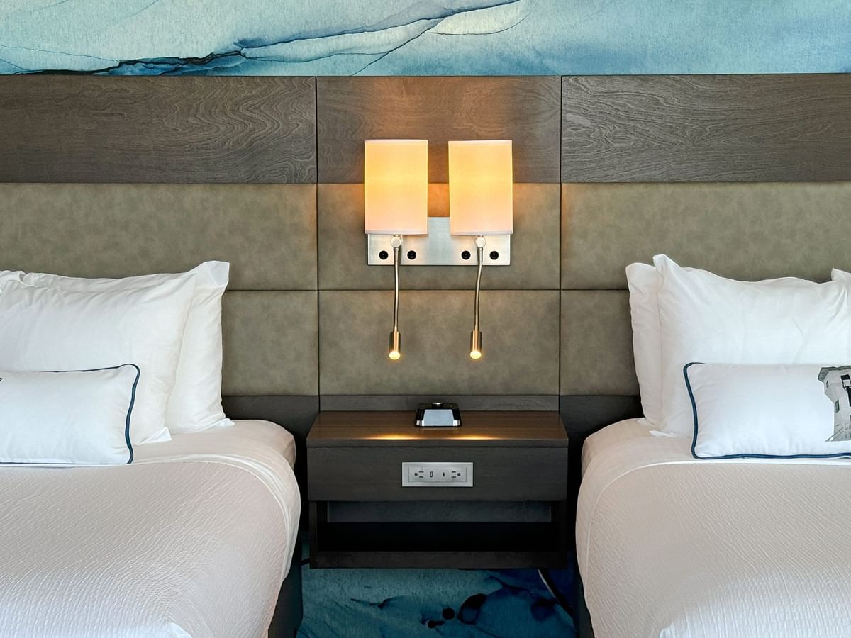 Hotel guestroom with two queen beds, a nightstand and light