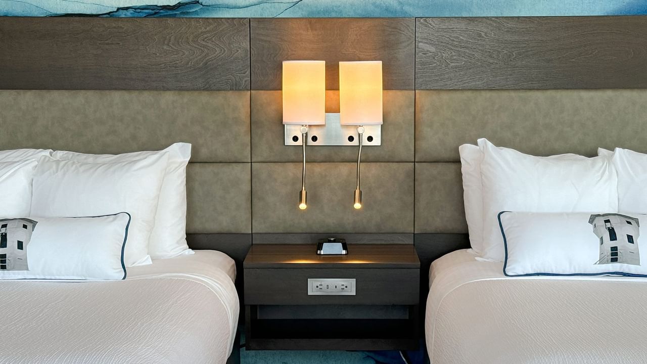 Hotel guestroom with two queen beds, a nightstand and light