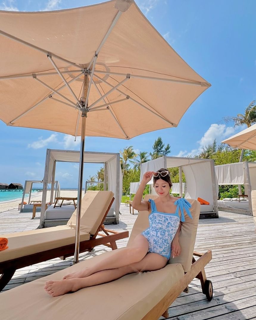 Lady on a sun lounger under an umbrella by the pool at Park Hotel Group