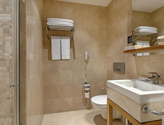 Titanic Deluxe Lara – Junior Suite’te duşakabinli, tuvaletli ve havlulu lüks banyo.