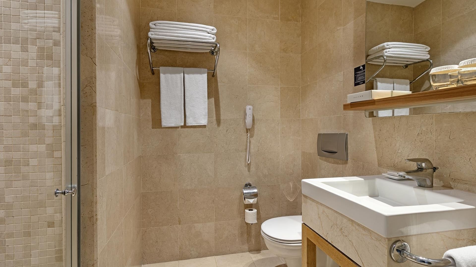 Titanic Deluxe Lara – Junior Suite’te duşakabinli, tuvaletli ve havlulu lüks banyo.