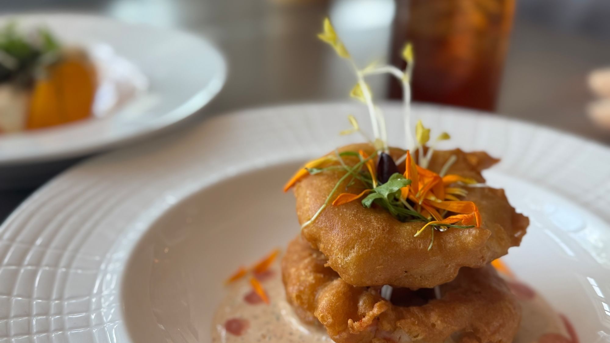 Savory fried green tomatoes with herbs on white plate showcasing Watersound Dining Package.
