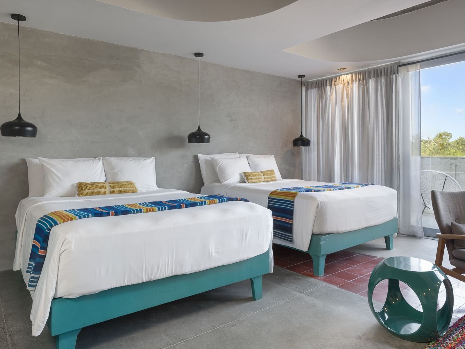 Two beds, a chair, and a side table in a room at El Blok in Vieques.