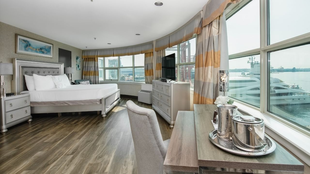 Coast Carrie Cates Penthouse Suite  featuring large windows, a bed, a dresser, desk at Coast Lonsdale Quay Hotel