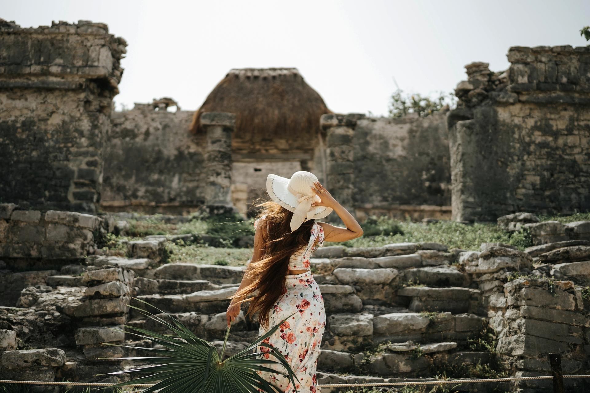 Woman in a floral dress and sun hat explores the ancient Mayan ruins near the lovely La Zebra Hotel
