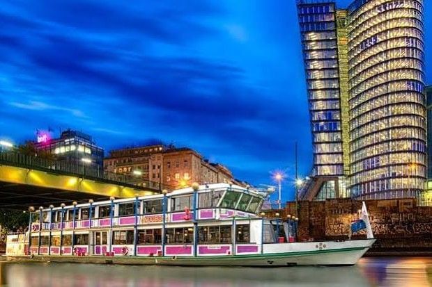 Abendfahrt auf dem Wiener Donaukanal mit Ausflugsschiff, beleuchteter Skyline und moderner Architektur