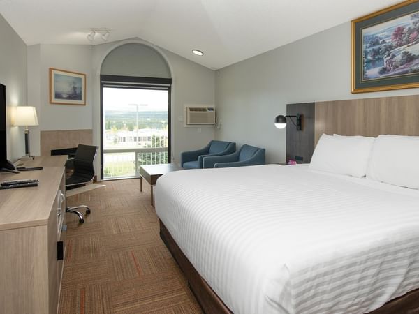 Coast King room with king bed, work desk, blue sofa and arched window.