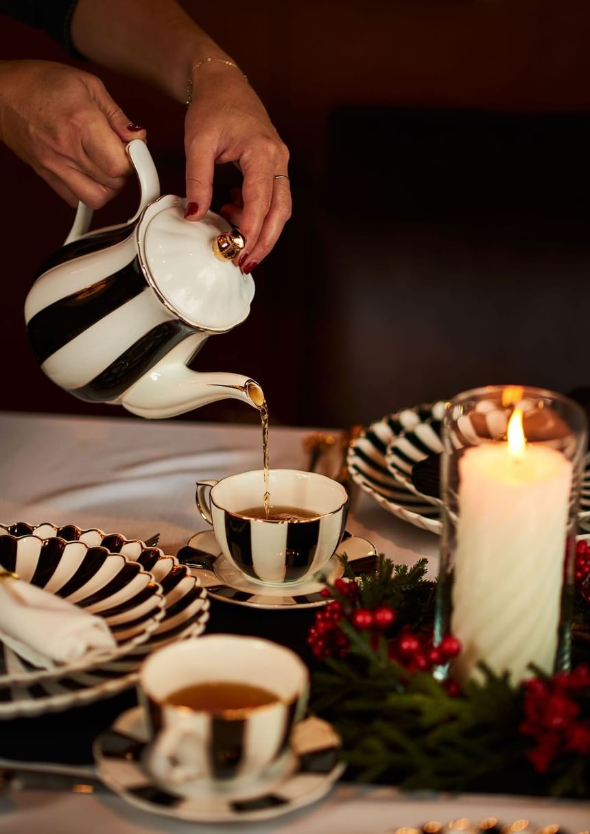 Person pouring tea from a teapot into a cup on a festive table at Hotel Arista