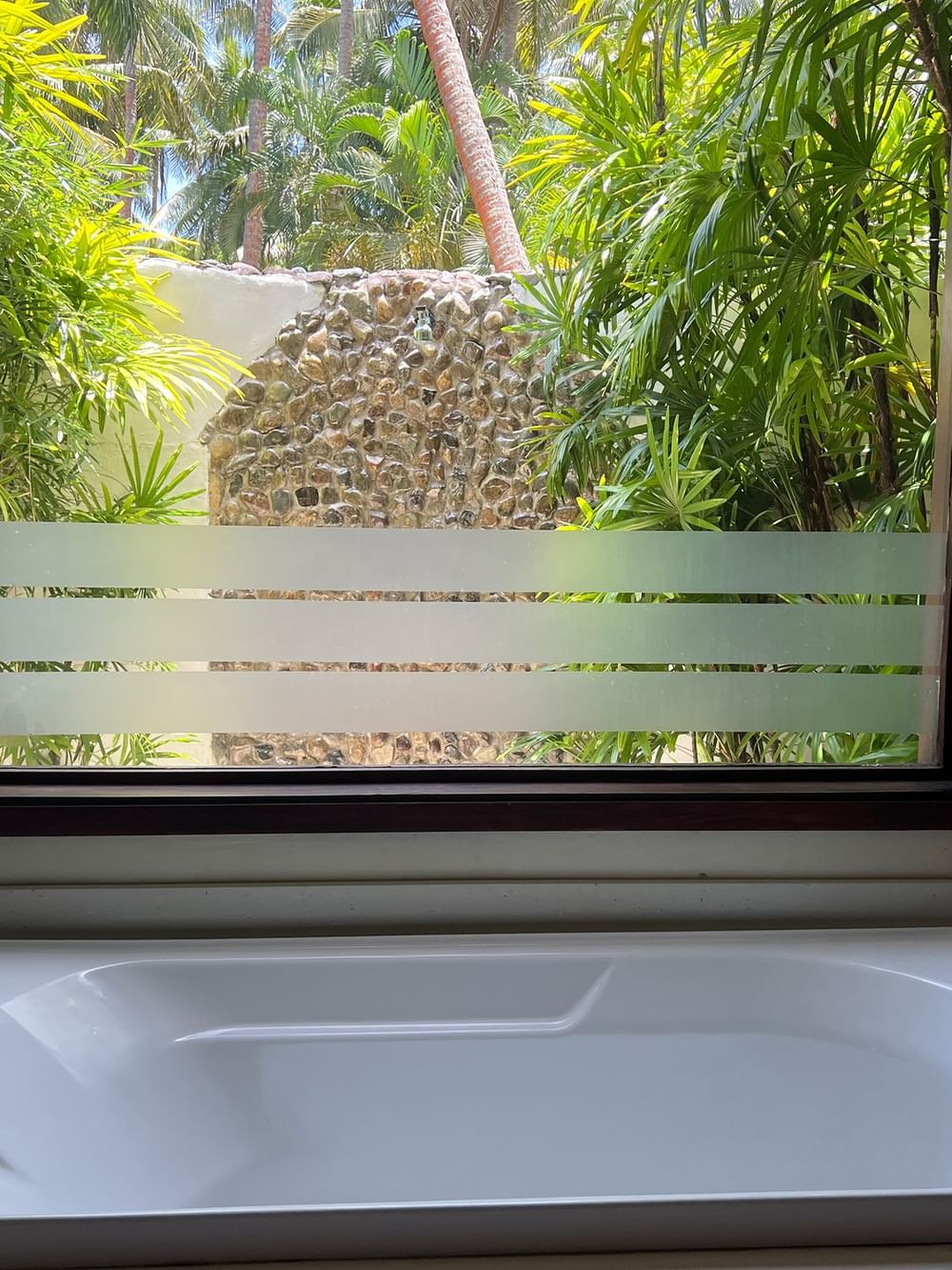 White bathtub with a window view of tropical plants at Tambua Sands Beach Resort in Sigatoka.