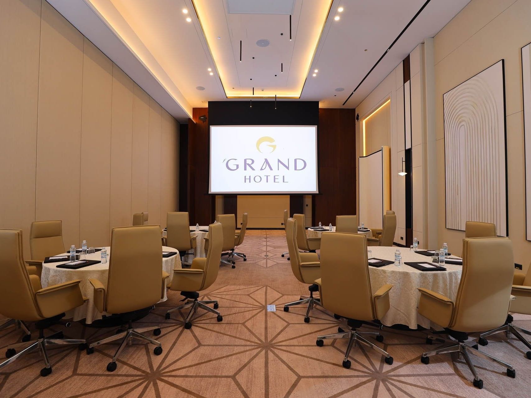 Chairs around tables in a conference room with a large screen displaying 