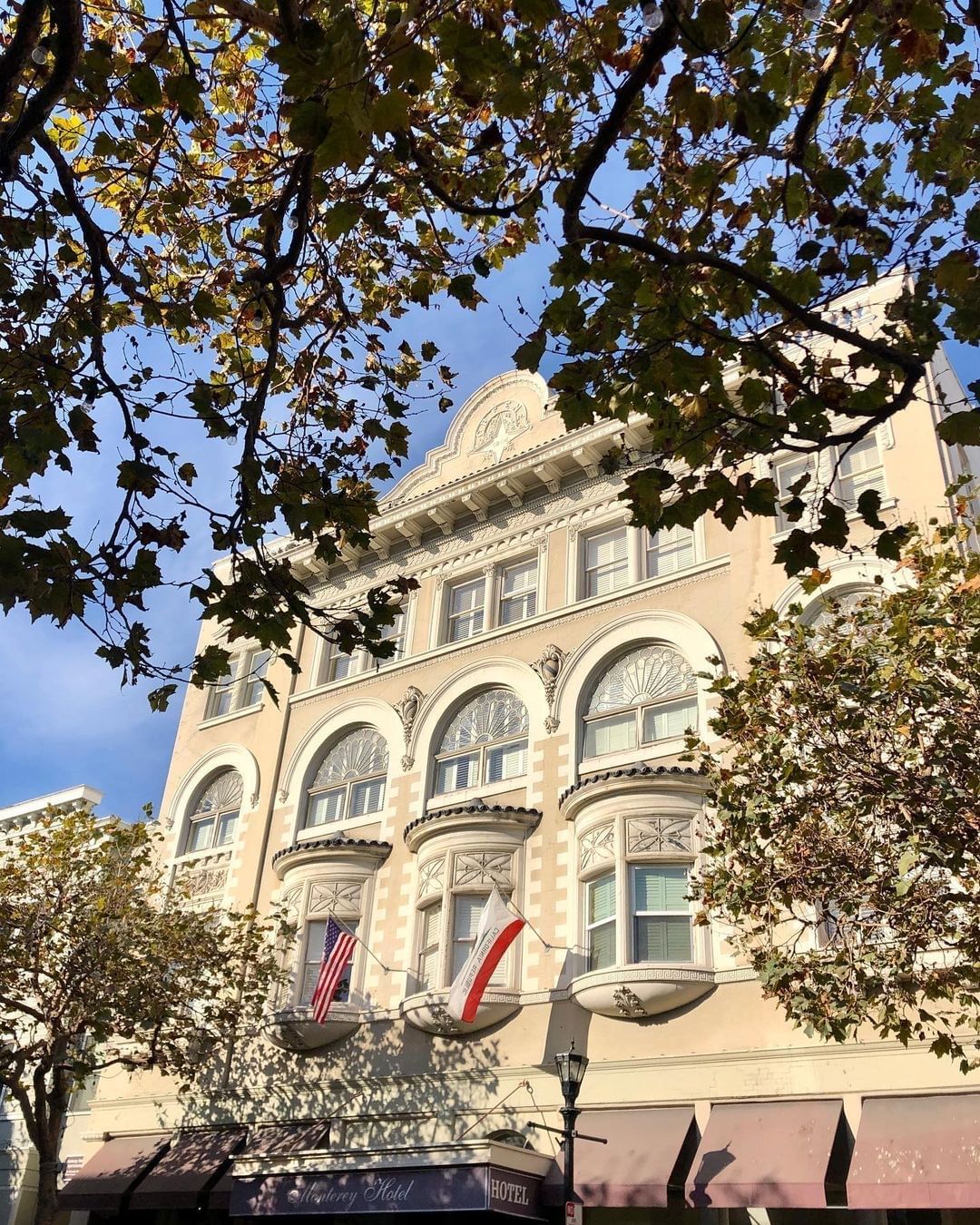 A low-angle shot of a hotel building with trees in front of it.