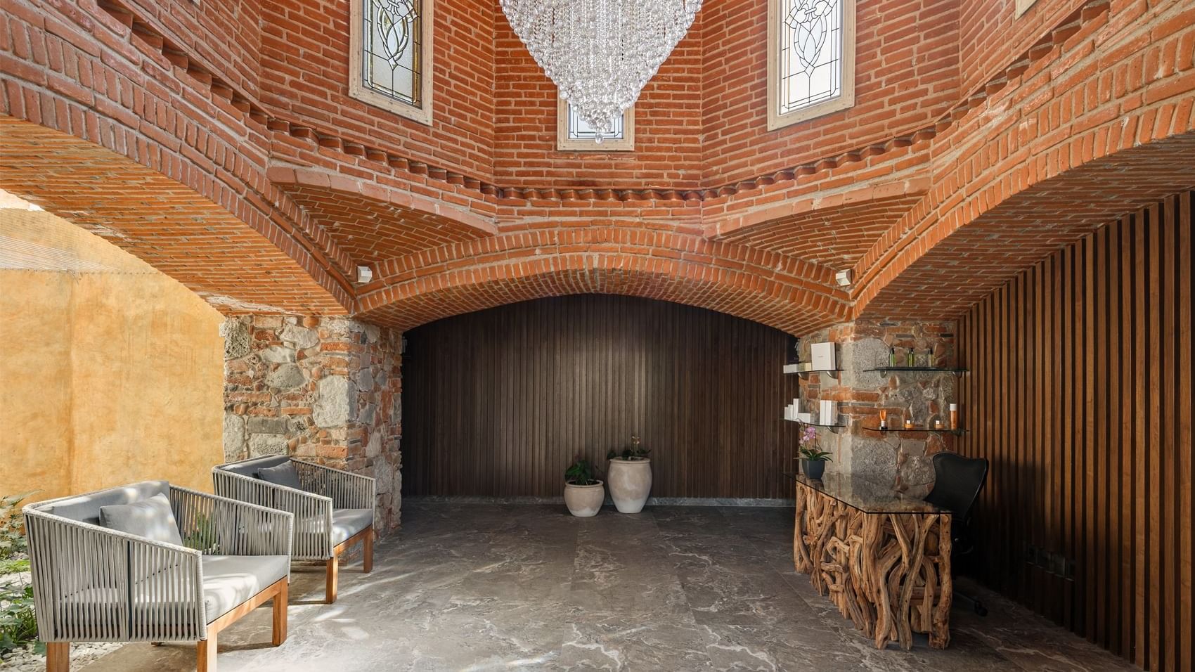 Lobby near Fiesta Americana, featuring a dazzling crystal chandelier, exposed brick arches, and a unique reception desk