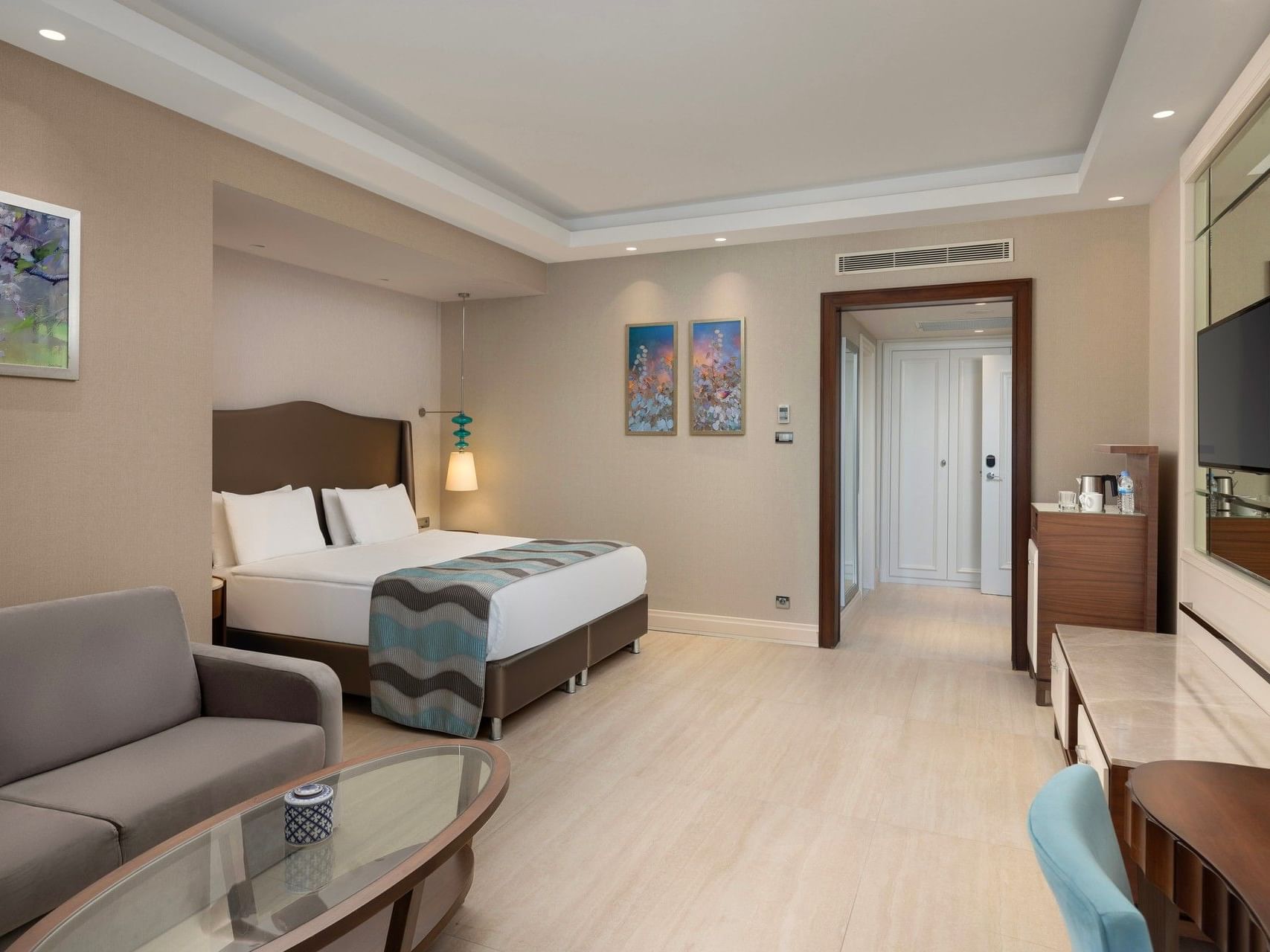Spacious hotel room with modern furnishings, light wood flooring, and neutral tones at Titanic Deluxe Golf Belek