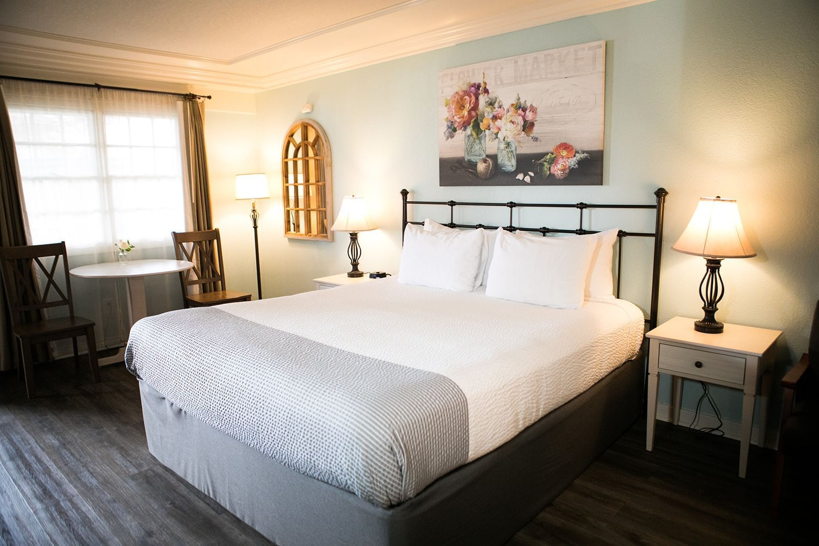 A hotel room with a large bed, nightstands, lamps, and artwork on the wall.