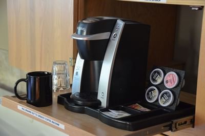 Keurig coffee maker sits on a slide-out tray with a black mug placed beside the brewer in a room at Hilltop Inn, Salmon Arm