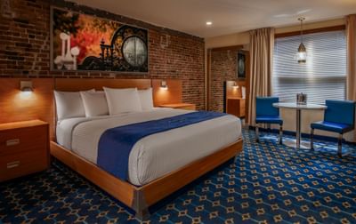 King bed with brick wall and window featuring art above headboard in King Atrium View at Harborside Inn Boston