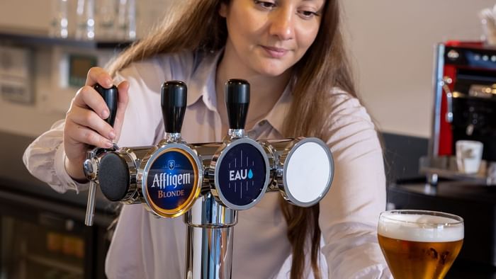 A bar maid filling beer into glasses at The Originals Hotels