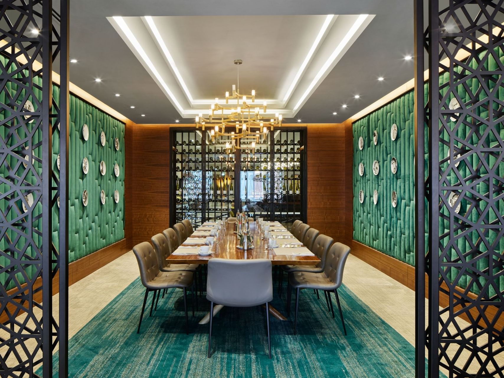 Eleganter Speisesaal mit Holztisch, grünen Wänden, schwarzen Trennwänden und Kronleuchter – Titanic Chaussee Berlin.