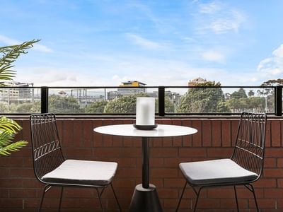 Outdoor seating with two chairs and a table on a balcony at Caulfield Place.