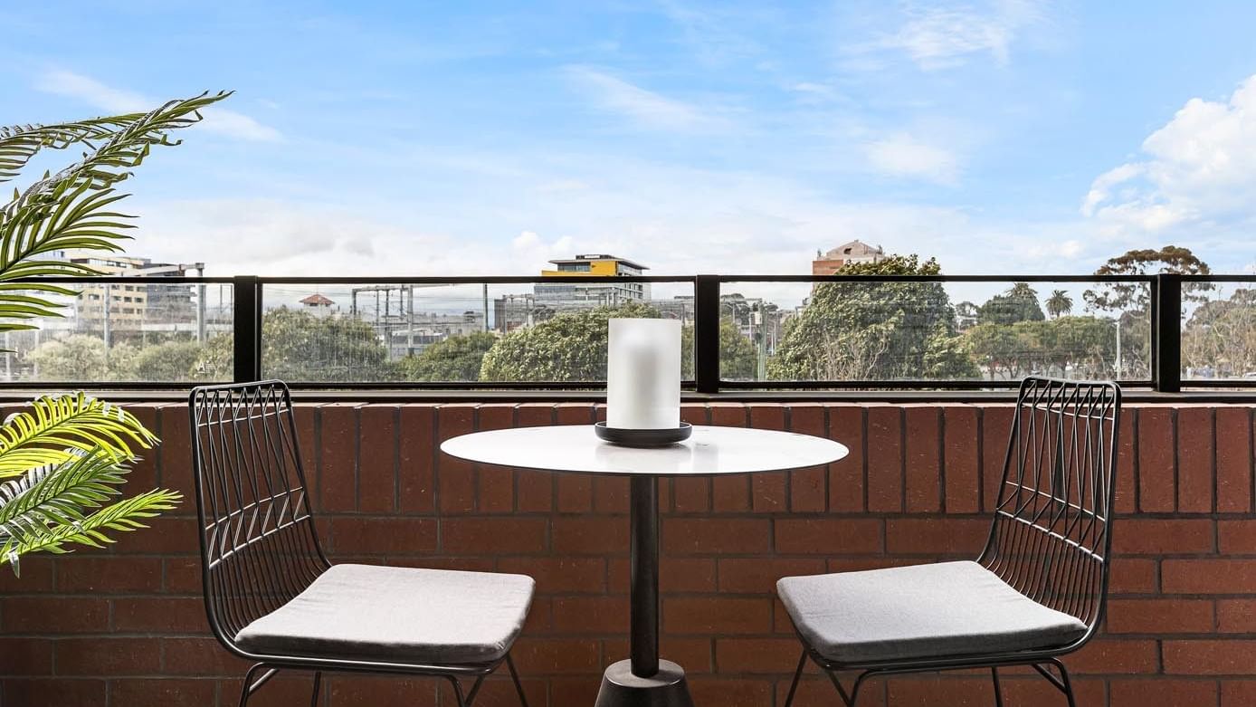 Outdoor seating with two chairs and a table on a balcony at Caulfield Place.