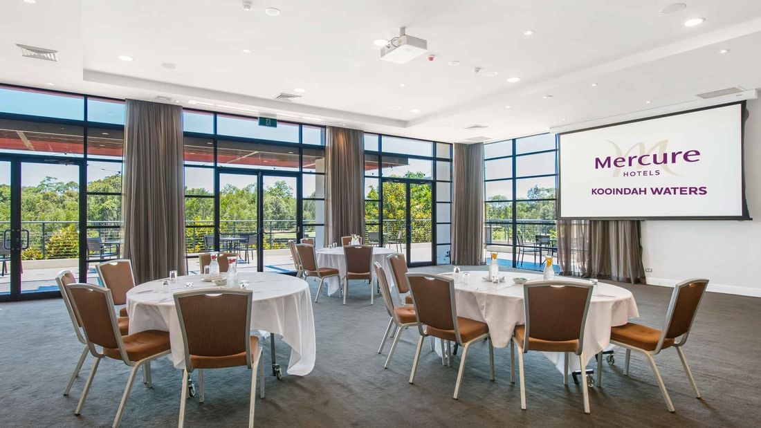Kooindah Three conference room with tables, chairs, and large windows overlooking trees at Mercure Kooindah Waters