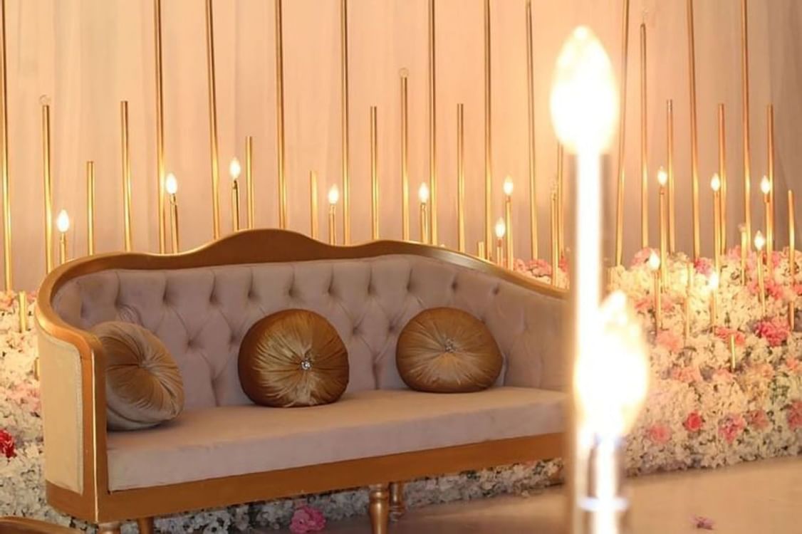 Velvet sofa with round cushions by a floral display and gold rods in a venue at Warwick Al Jubail