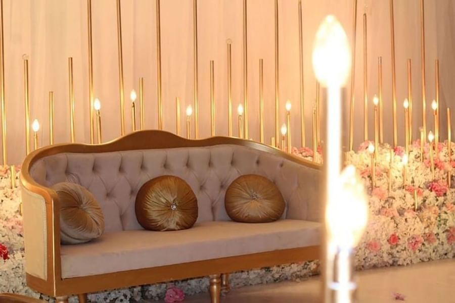 Velvet sofa with round cushions by a floral display and gold rods in a venue at Warwick Al Jubail