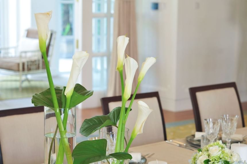 Dining table featuring tall white calla lilies in glass vases, in a bright indoor space at Park Hyatt Saigon