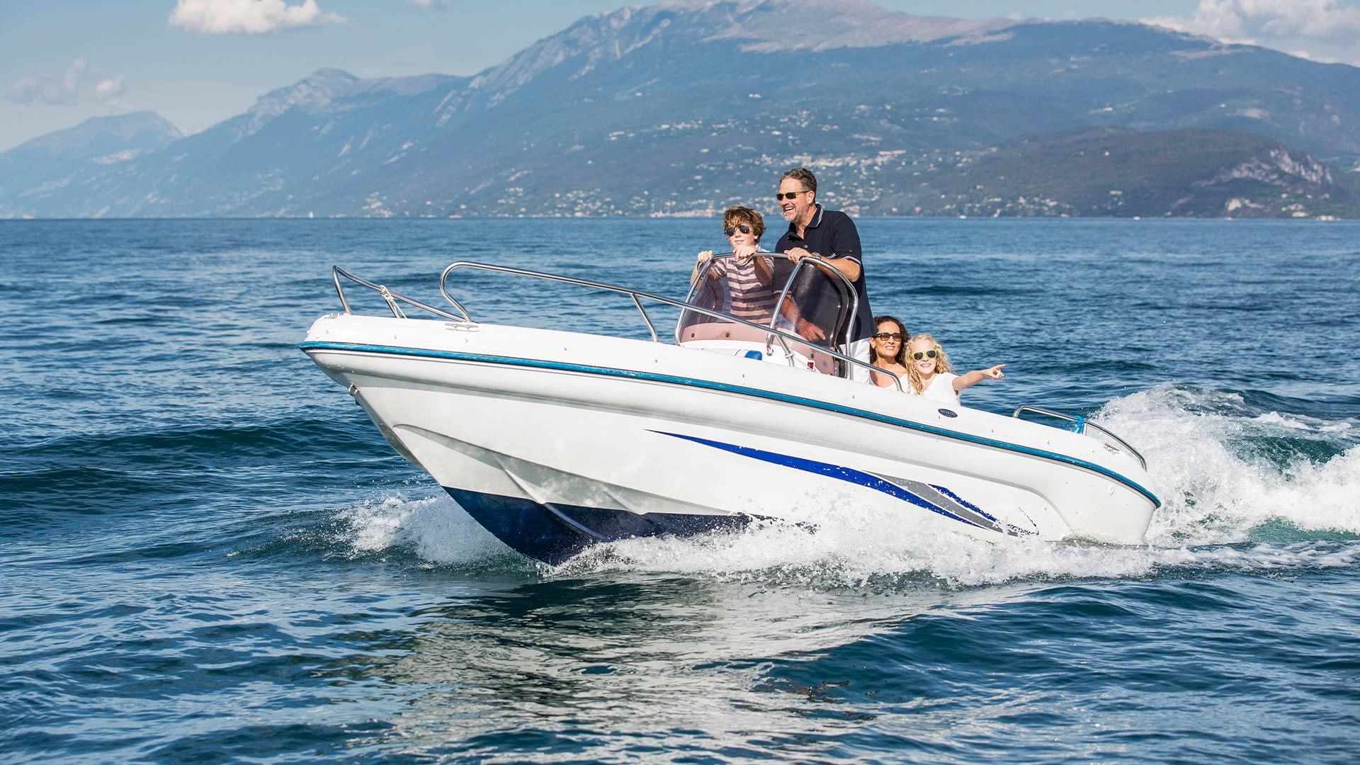 Family enjoying a boat ride on Lake Garda with mountains in the background at Falkensteiner Resort.