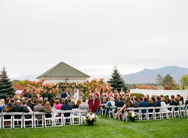 Guests watching vows exchanged by a hydrangea-covered pavilion, near the mountains at Mountain View Grand Resort & Spa
