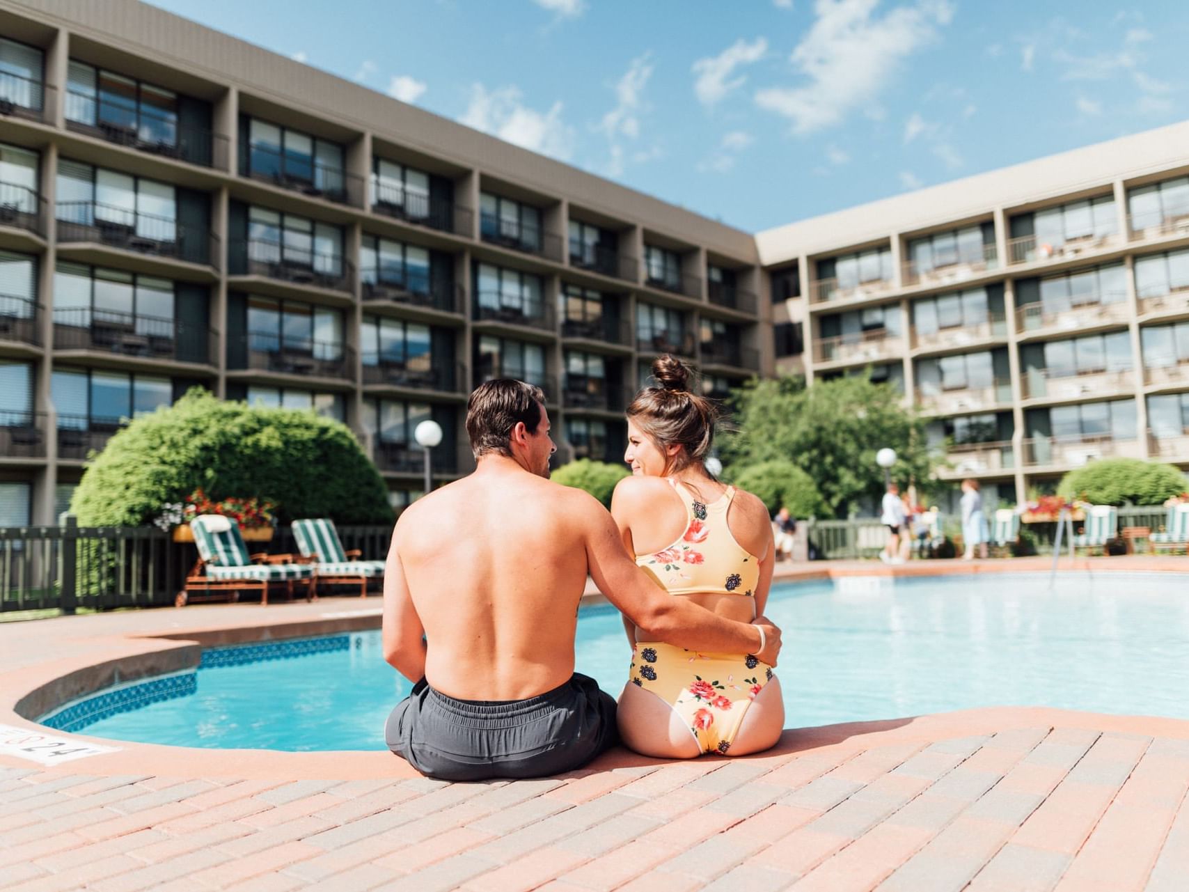 A couple seated on an edge at courtyard pool in High Peaks Resort