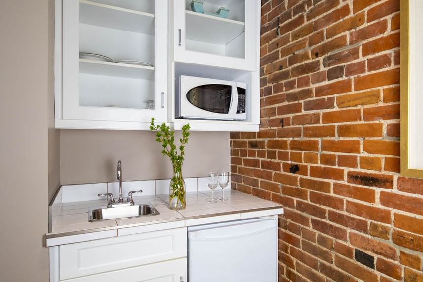 Kitchenette with pantry, appliances & brick wall in Queen Premiere Chardonnay at Retro Suites Hotel
