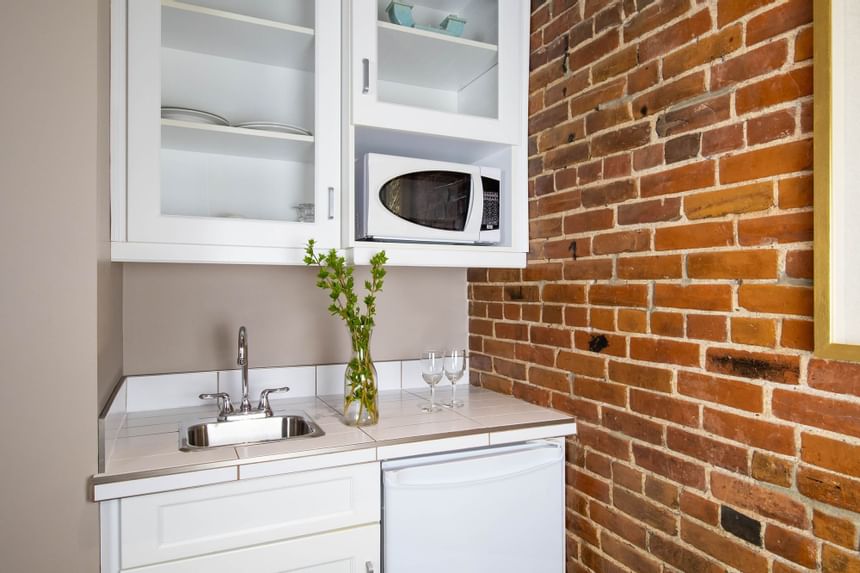 a kitchenette with a sink and microwave, exposed brick 
