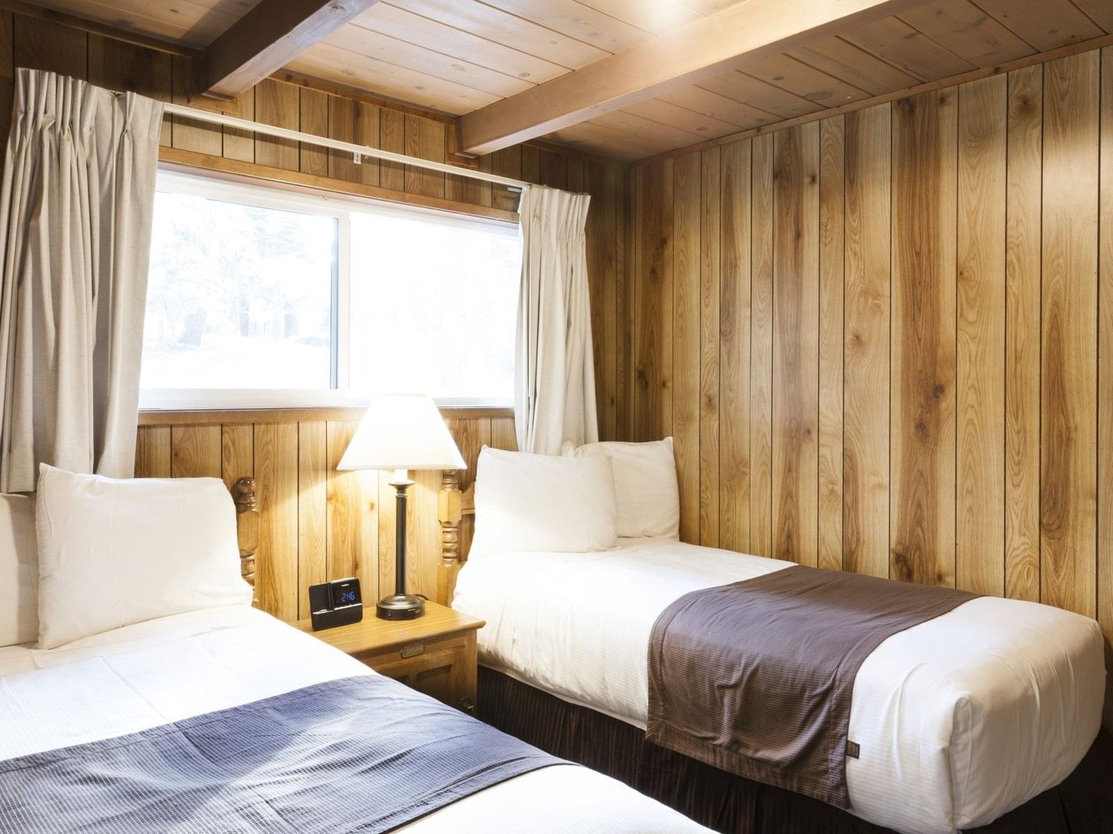 Wooden cabin with twin beds and nightstand at Alpenhof Lodge