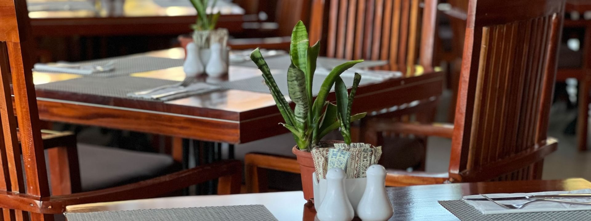 Wooden dining tables and chairs set at Bula Brasserie in Korolevu at Warwick Fiji Resort and Spa