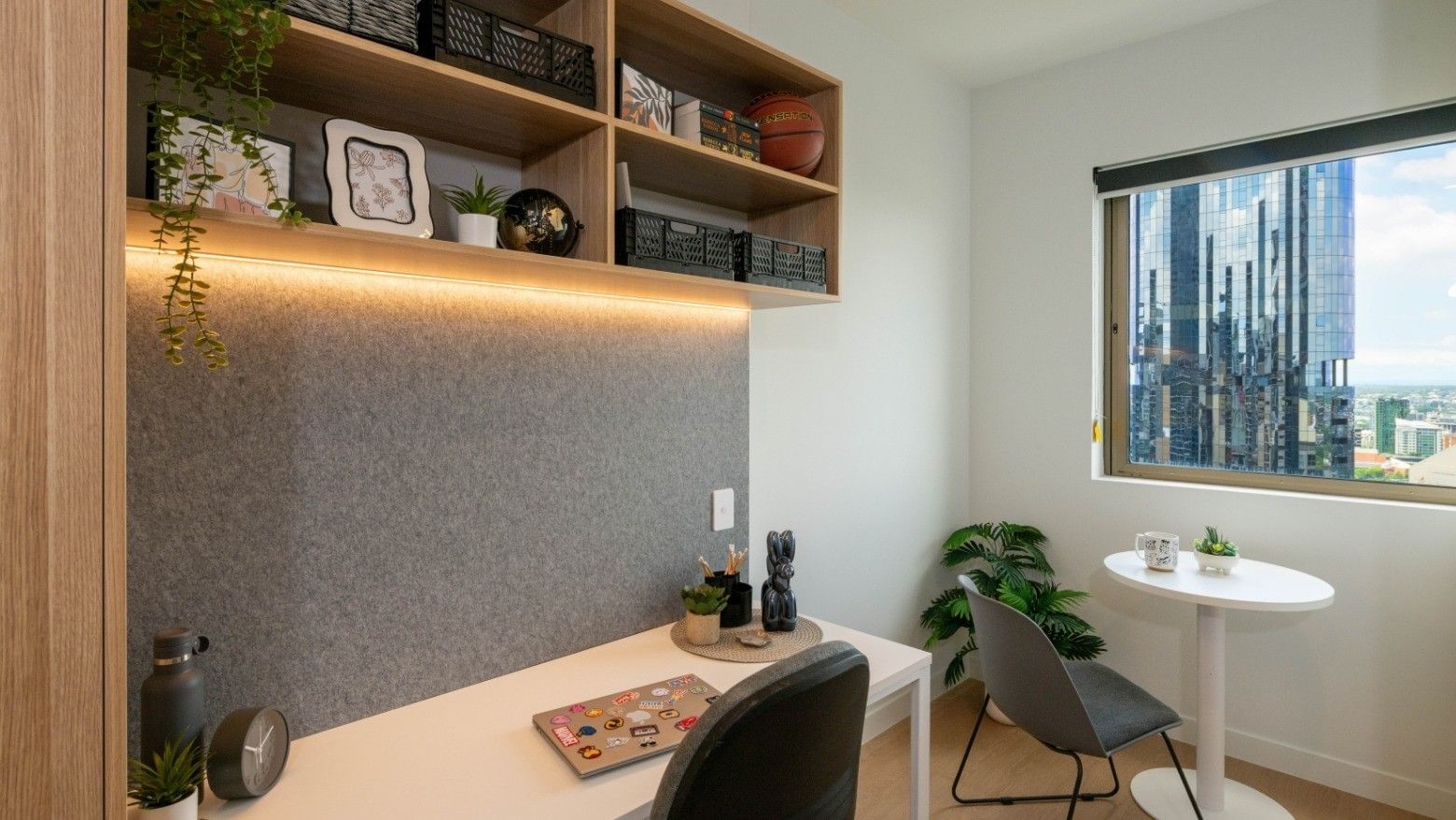 Modern office space with desk, chair, plants, and city view at UniLodge Brisbane City.