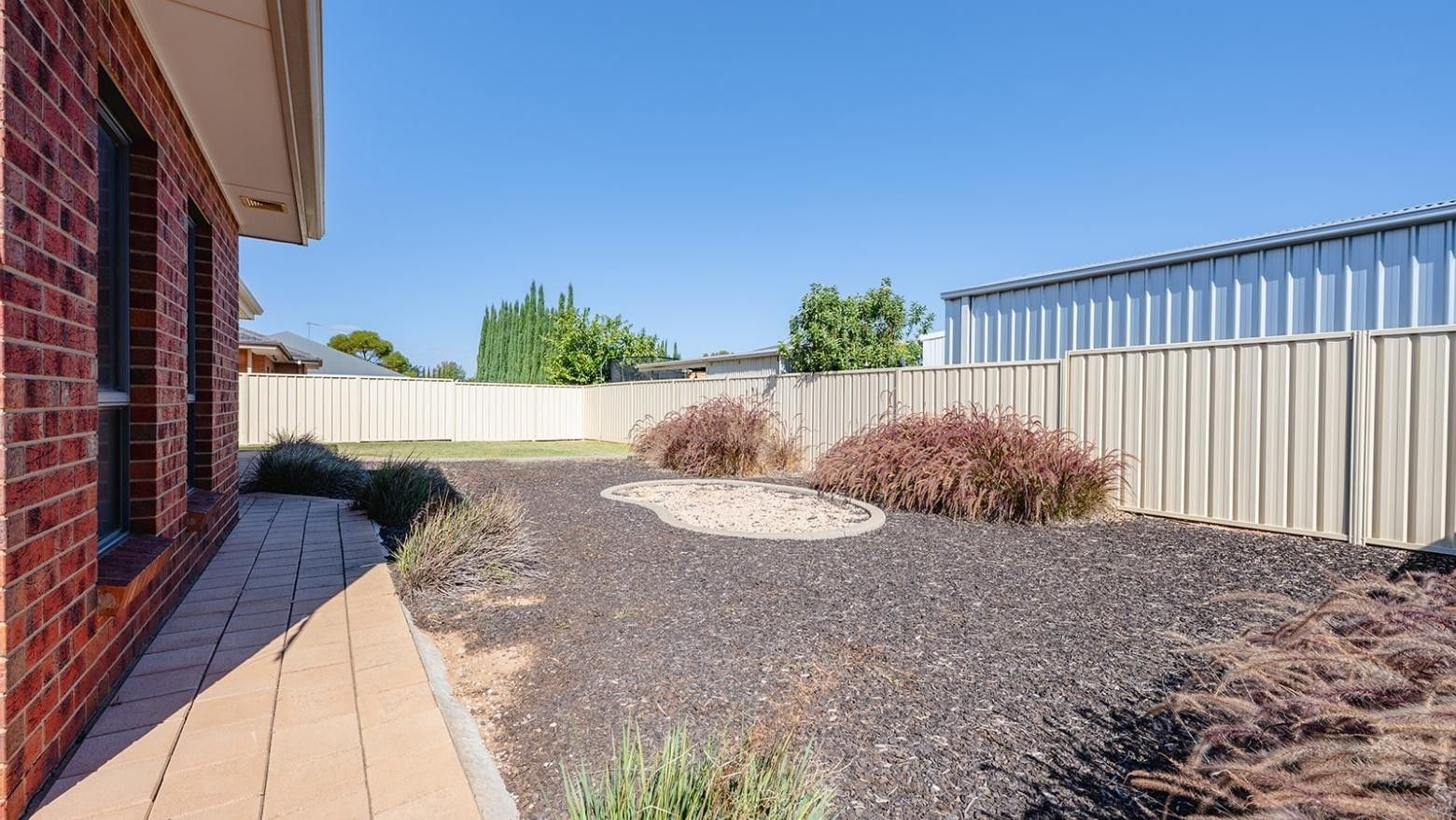Backyard with a brick house and fenced yard at La Trobe University Regional Housing – Mildura.