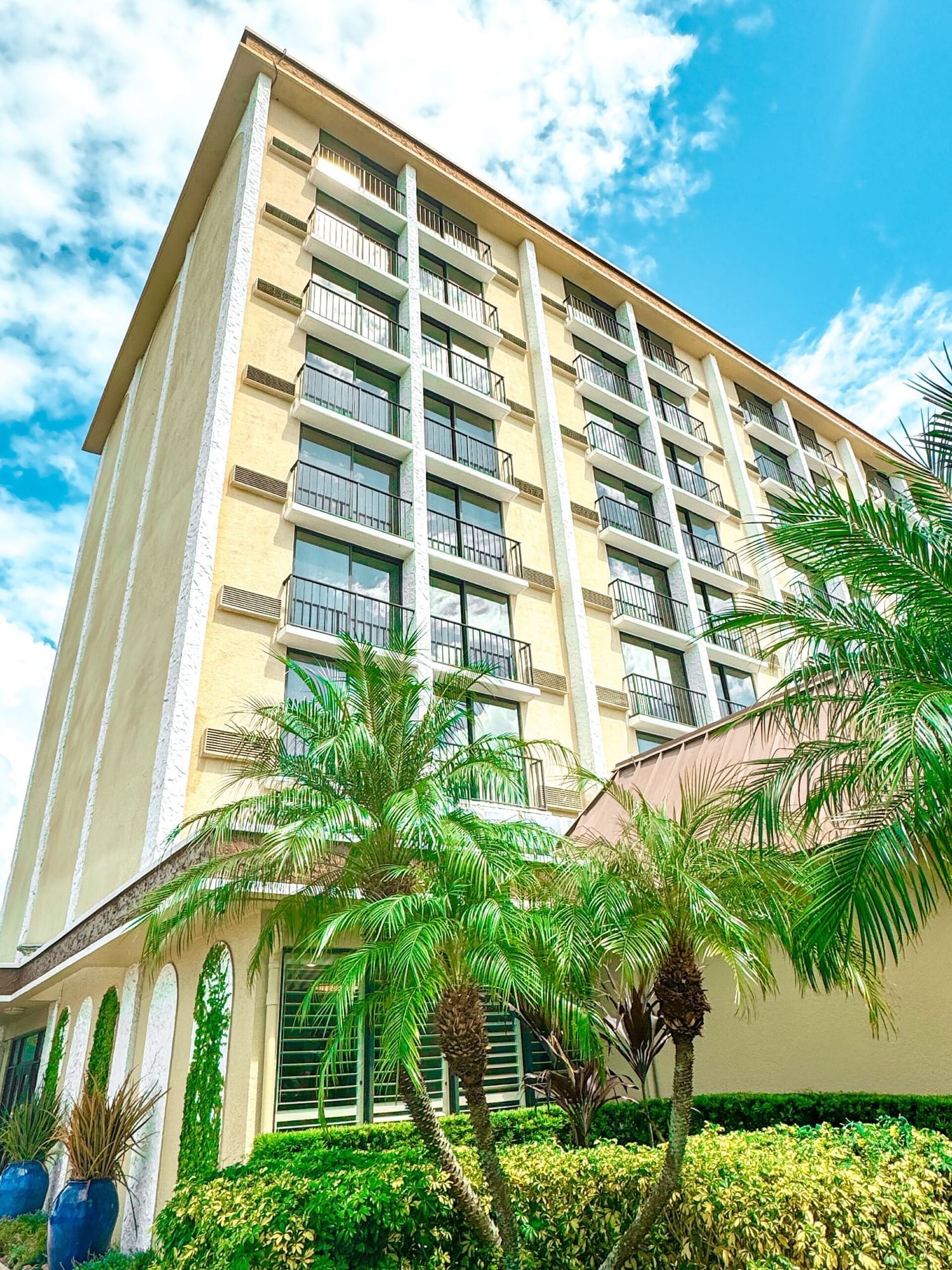 The corner of a tall building covered in windows against a cloudy blue sky. Stay at Rosen Inn closest to Universal for Single's Awareness Day.