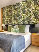 Decorative floral wall with large bed beside small sofa in Lagoon Superior Room at warwick le lagon-vanuatu